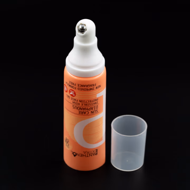 Orange airless tube with metal applicator tip and clear cap, cap off