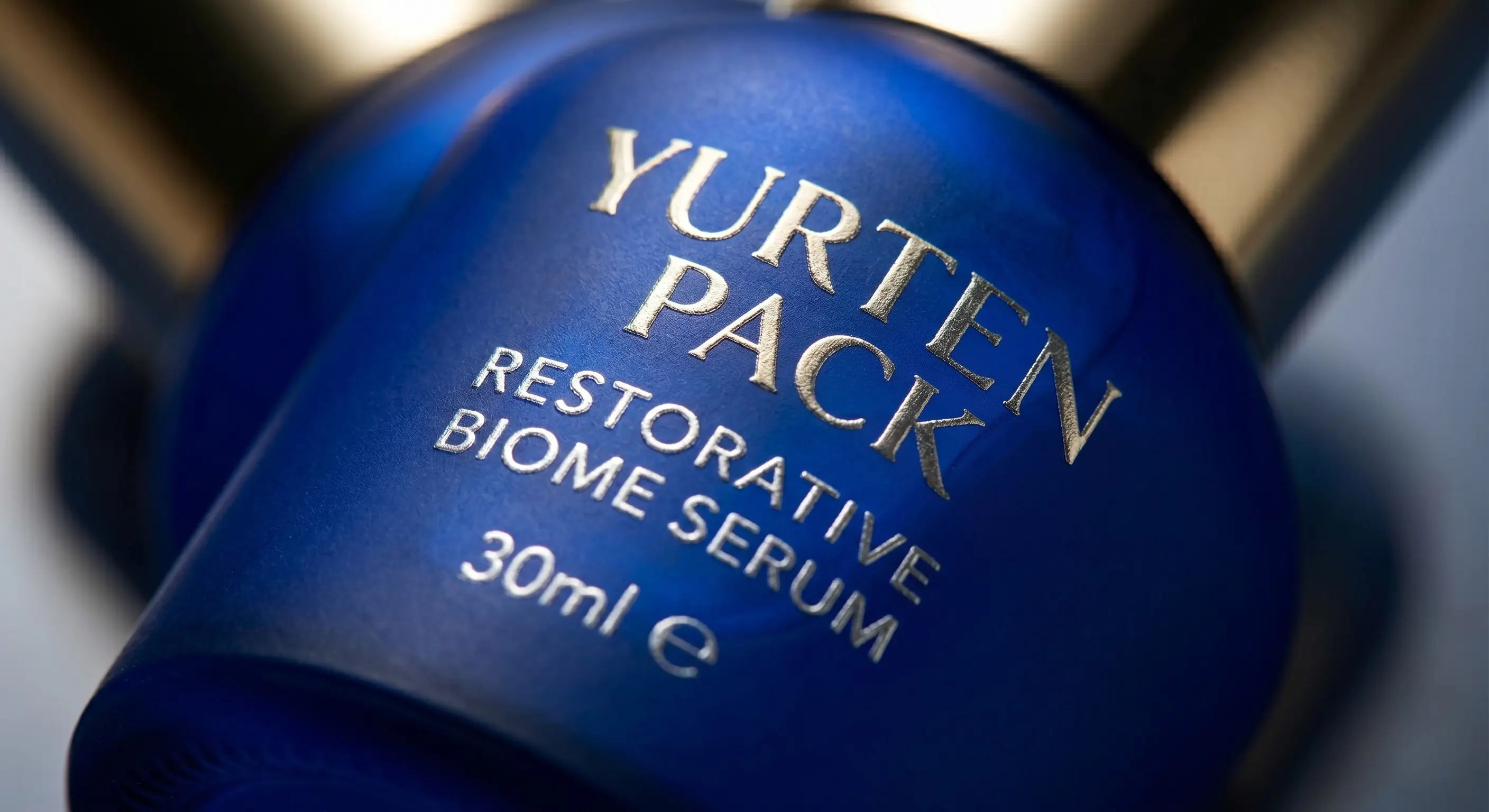 Matte cobalt serum cylinder with mirrored silver silkscreen artwork.